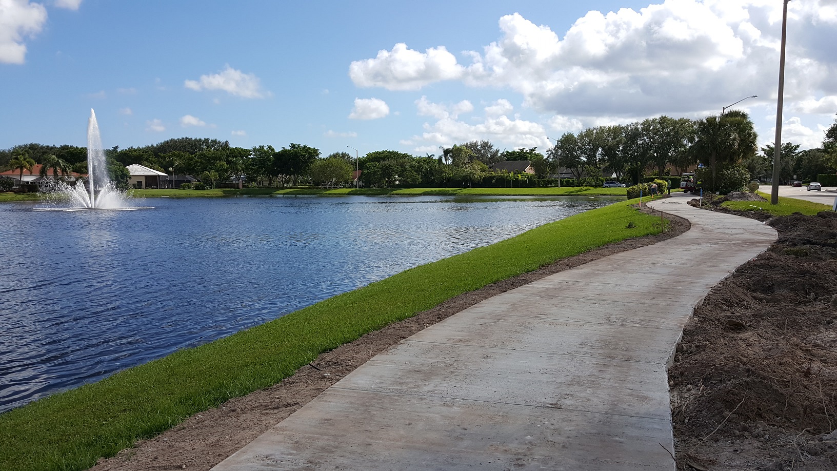 Paved walkway with lake fountain in distance